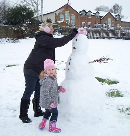 Candice helps daughter Lily-mae to build a snowman in Barry's meadow, Titchfield