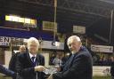 Peter Raynbird (left) being presented with a crystal bowl on the pitch by Mick Davis