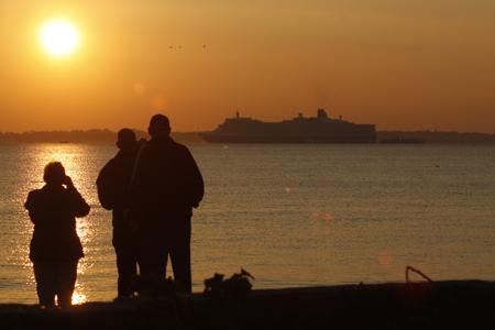 Maiden Voyage: Spectators watch from Hill Head as Cunard's Queen Elizabeth sails off into the sunset. Picture Phil Burner