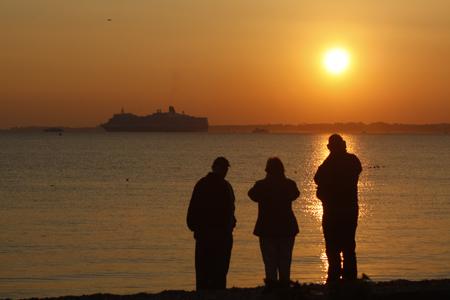 Maiden Voyage: Spectators watch from Hill Head as Cunard's Queen Elizabeth sails off into the sunset. Picture Phil Burner