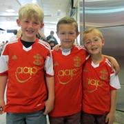 Three young Saints fans enjoy getting their hands on the new shirt on the day it came out.