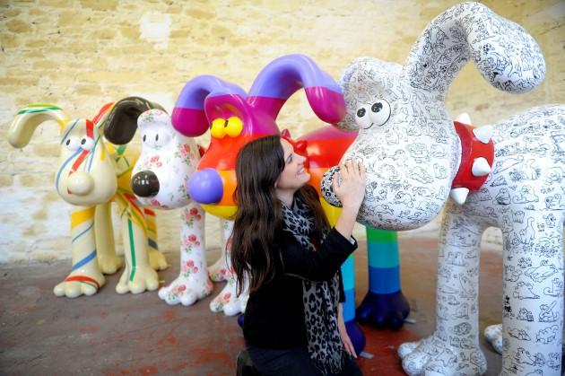 Lauren Vincent, fundraising manager for Gromit Unleashed, poses with four, of around 70, Gromit sculptures painted by (left to right) Sir Paul Smith, Cath Kidston, Richard Williams and Simon Tofield, at a secret location in Bristol before they are placed 