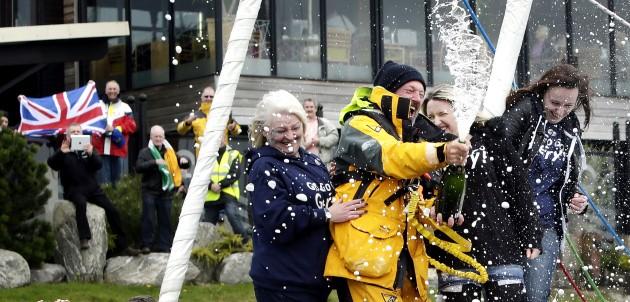 Gerry Hughes opens a bottle of Champagne with his wife Kathleen (left) and daughters Ashley (2nd right) and Nicola (right), after arriving at Troon Marina in Scotland to make him the first deaf person to have sailed single-handed around.
Picture date: We