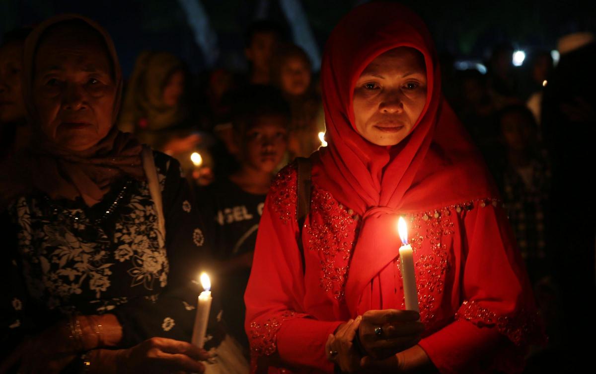 Indonesian women hold candles to pray for the victims of AirAsia Flight 8501 in Pangkalan Bun, Indonesia. Picture of the Day for January 2, 2015.