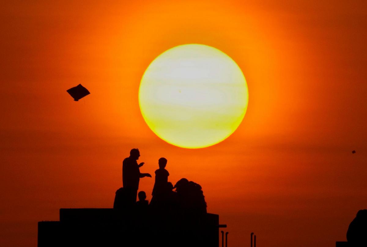 Indians
fly
kites
standing
on
the
roof
of
a
building
on
the
eve
of
Makar
Sankranti,
a
Hindu
harvest
fes-
tival,
also
known
as
kite
festival,
in
Ahmadabad,
India. Picture of the Day for January 14, 2015.