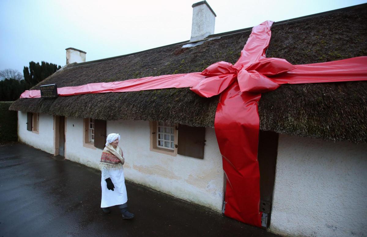 Alison
Wilson
walks
past
the
Robert
Burns
Cottage
in
Alloway. Picture of the day for January 26, 2015.