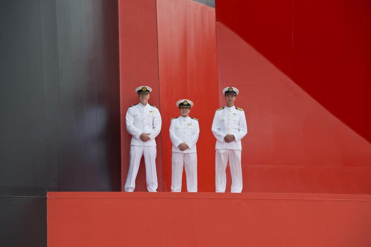 The three captains of the Three Queens in front of Queen Mary 2's funnel