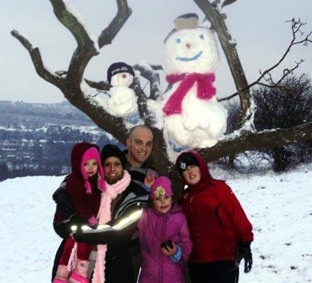 Snow covers Hampshire - Ryan, Lisa, Kyler and Layla with snowman up a tree on St Catherines Hill, Winchester