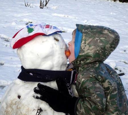Snow covers Hampshire - Kieran eating snowman's carrot nose by Sharon Davis