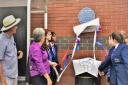 Alan Matlock, chair of The Spitfire Makers Charitable Trust, watches as Judy Theobald and students from Upper Shirley High School unveil the plaque to commemorate the Sunlight Laundry