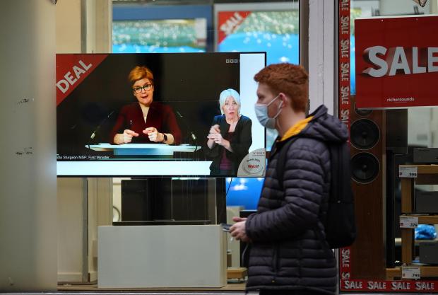Daily Echo: Passers-by look at a tv screen in a Glasgow shop showing First Minister Nicola Sturgeon making a Covid-19 statement during a virtual sitting of the Scottish Parliament. Photo taken on December 29, 2021, via PA.