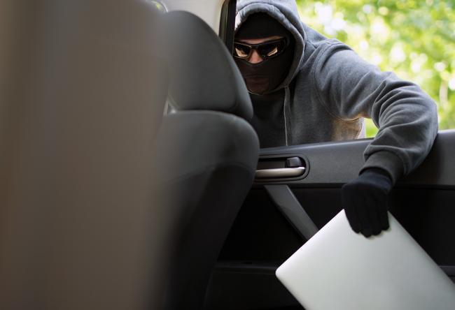 Stock photo of a man breaking into a car