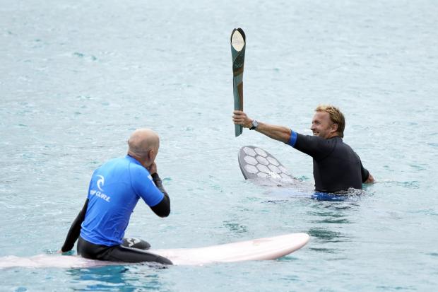 Batonbearer and founder of the Wave, Nick Hounsfield (right), holds The Queen's Baton as he surfs at The Wave in Bristol. PA Wire/PA Images