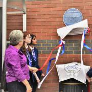 Alan Matlock, chair of The Spitfire Makers Charitable Trust, watches as Judy Theobald and students from Upper Shirley High School unveil the plaque to commemorate the Sunlight Laundry