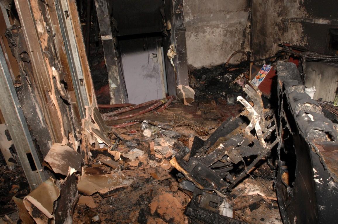 Another view of the lounge of flat 72, with the charred remains of a couch on the right hand side.