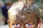 Harry Clitheroe, 10, is pictured covered in mud after tackling the obstacle course with his schoolmates